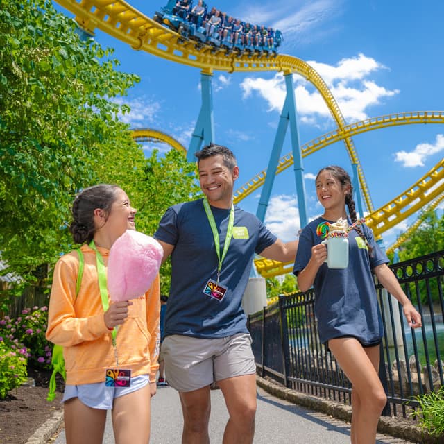 father and two daughters walking with skyrush in background
